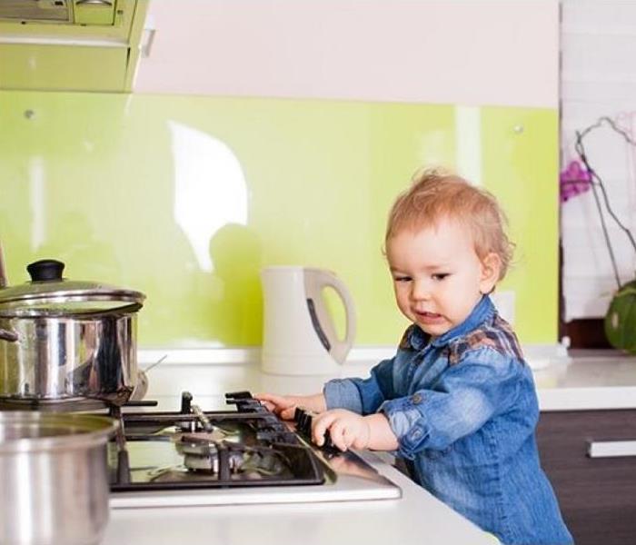 a toddler playing with stove knobs in kitchen