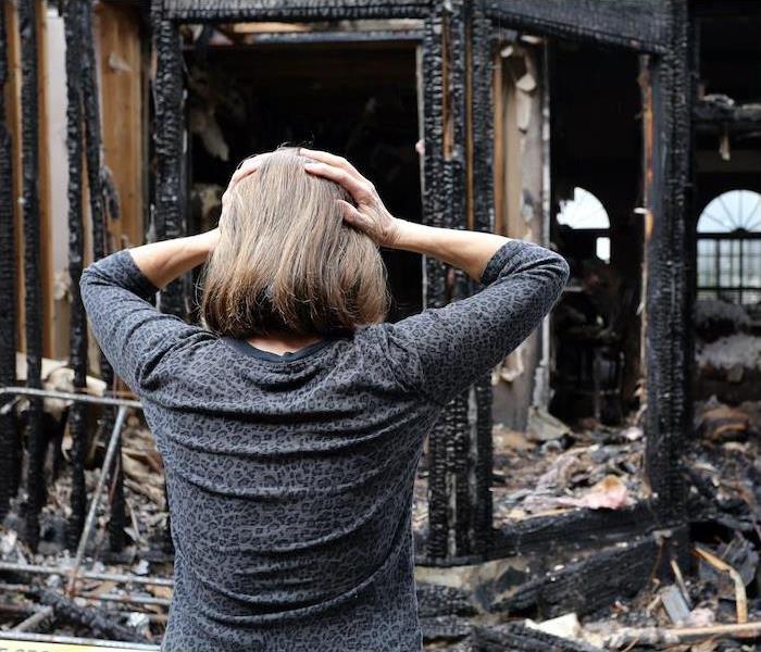 a person looking at a home completely destroyed by fire