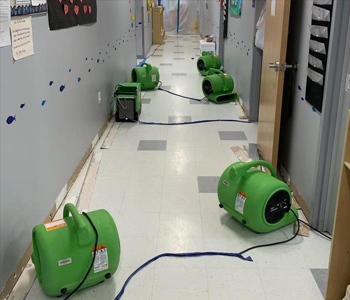 Air movers directed toward daycare walls to dry after water damage